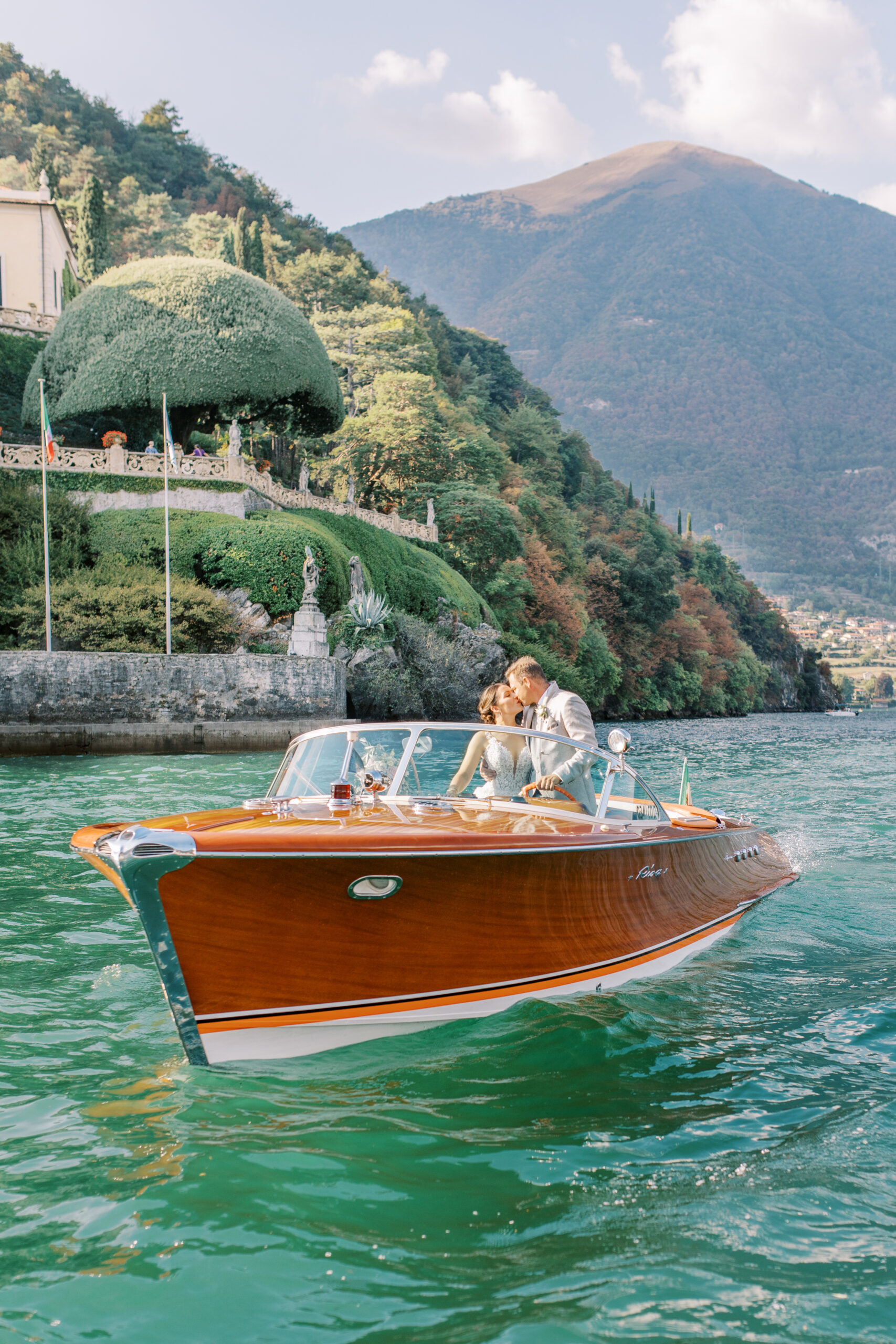 Bröllopsfotografering Villa Balbianello och paret står i en Riva-båt och pussas