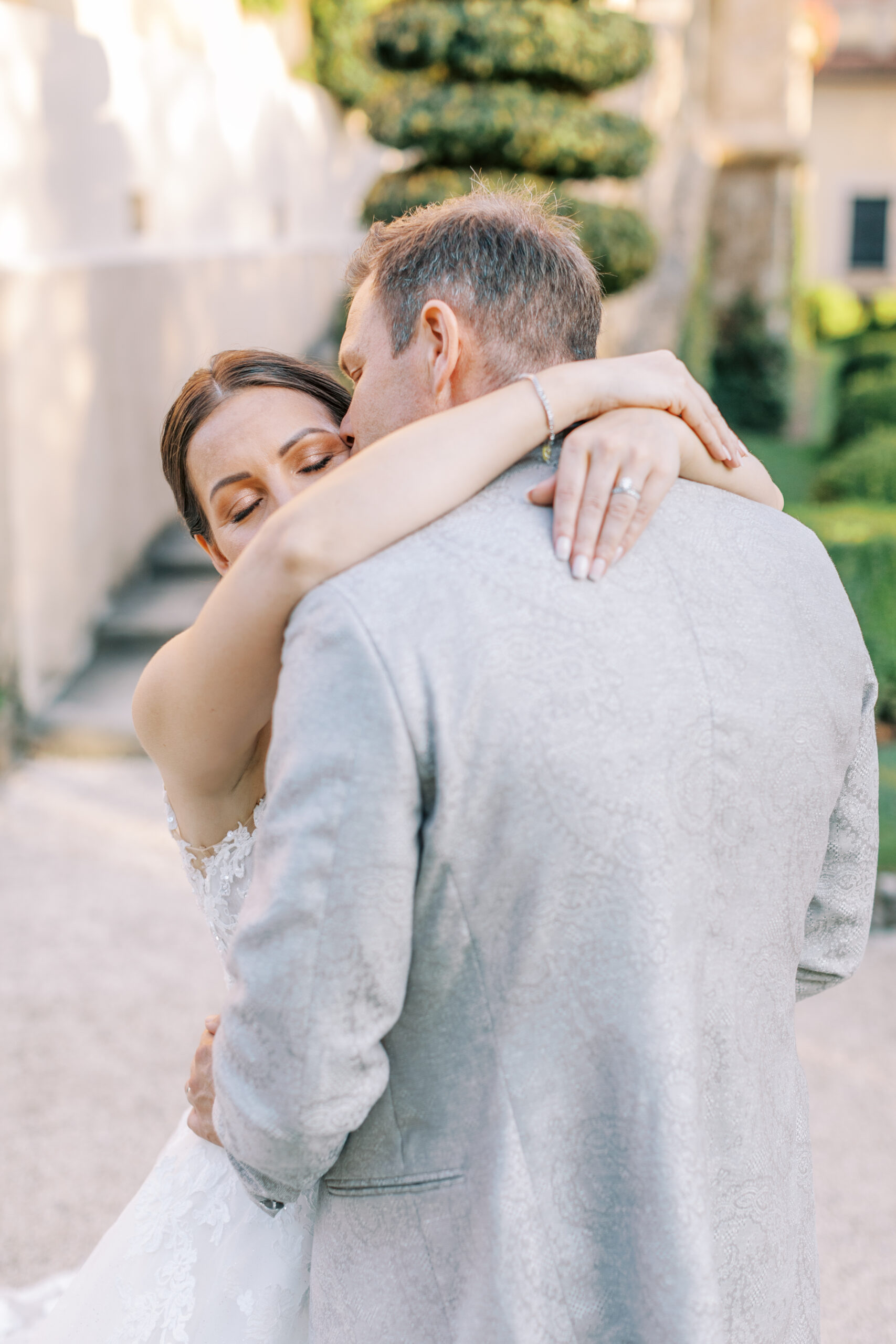 brollopsfotografering-como-italien brudgummen pussar bruden på tinningen och hon håller om hans hals