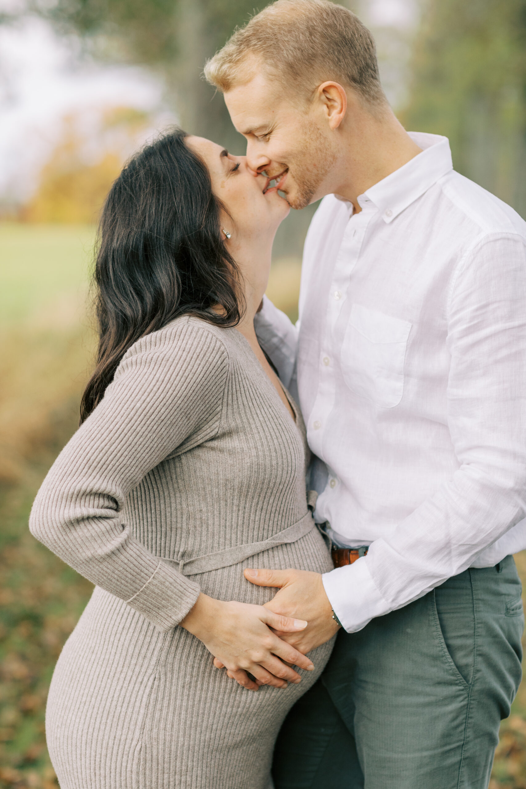 Gravidfotografering i Västerås där paret står mot varandra och pussas