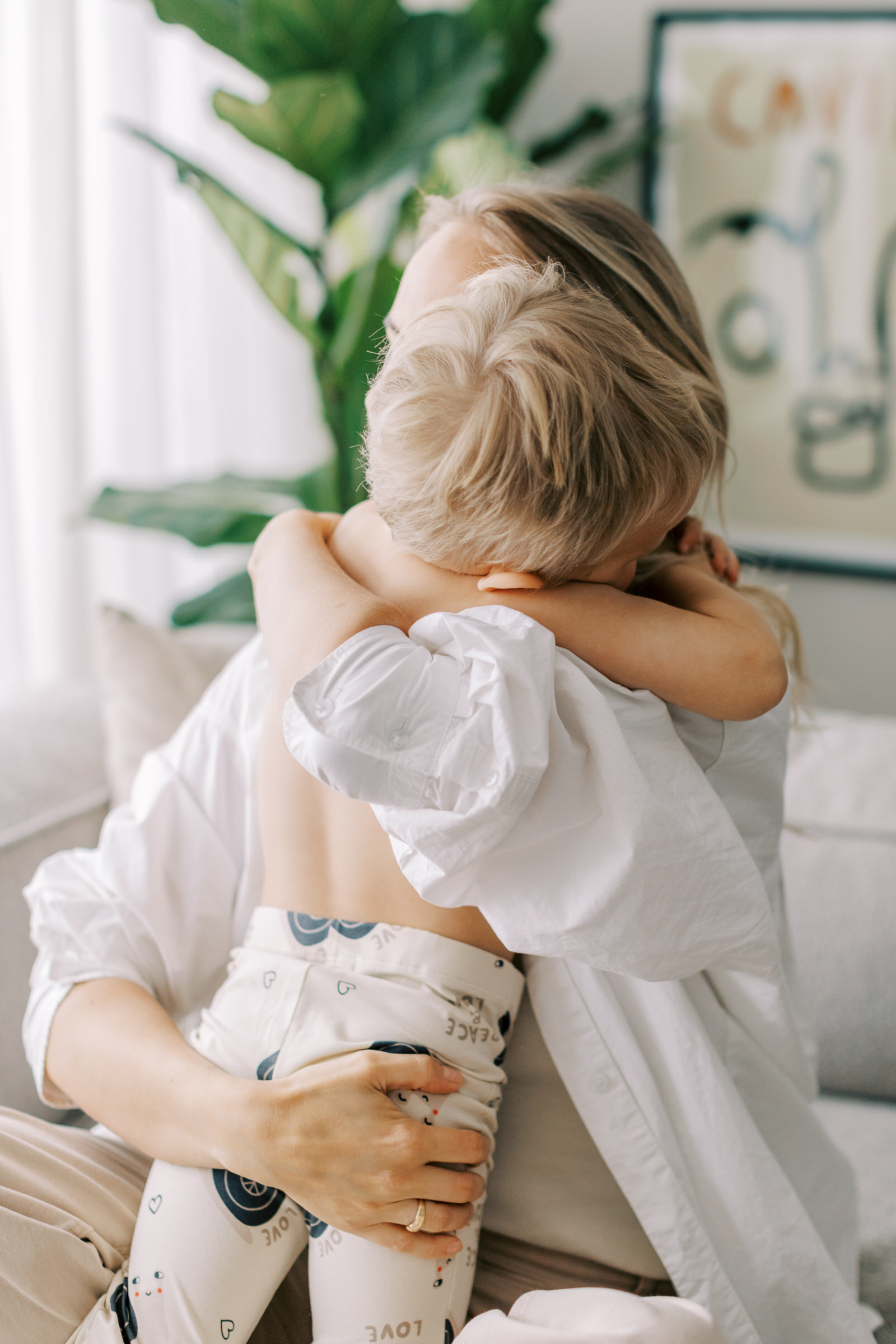 Familjefotografering i Västerås där sonen kramar om mamman i soffan