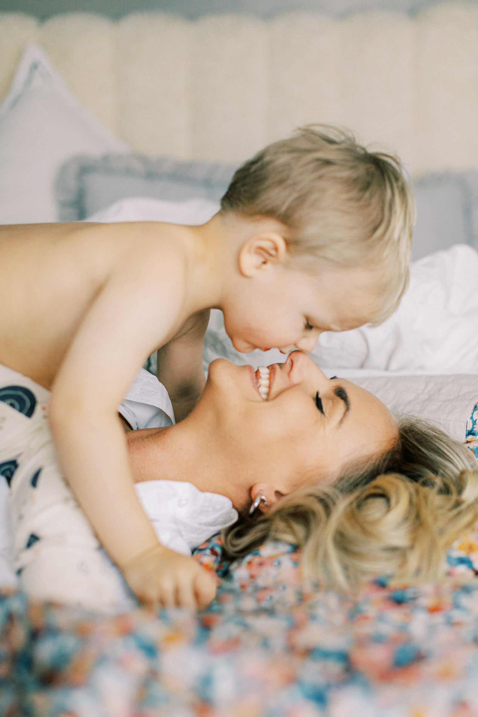 Familjefotografering i Västerås med en mamma och son gosar på sängen